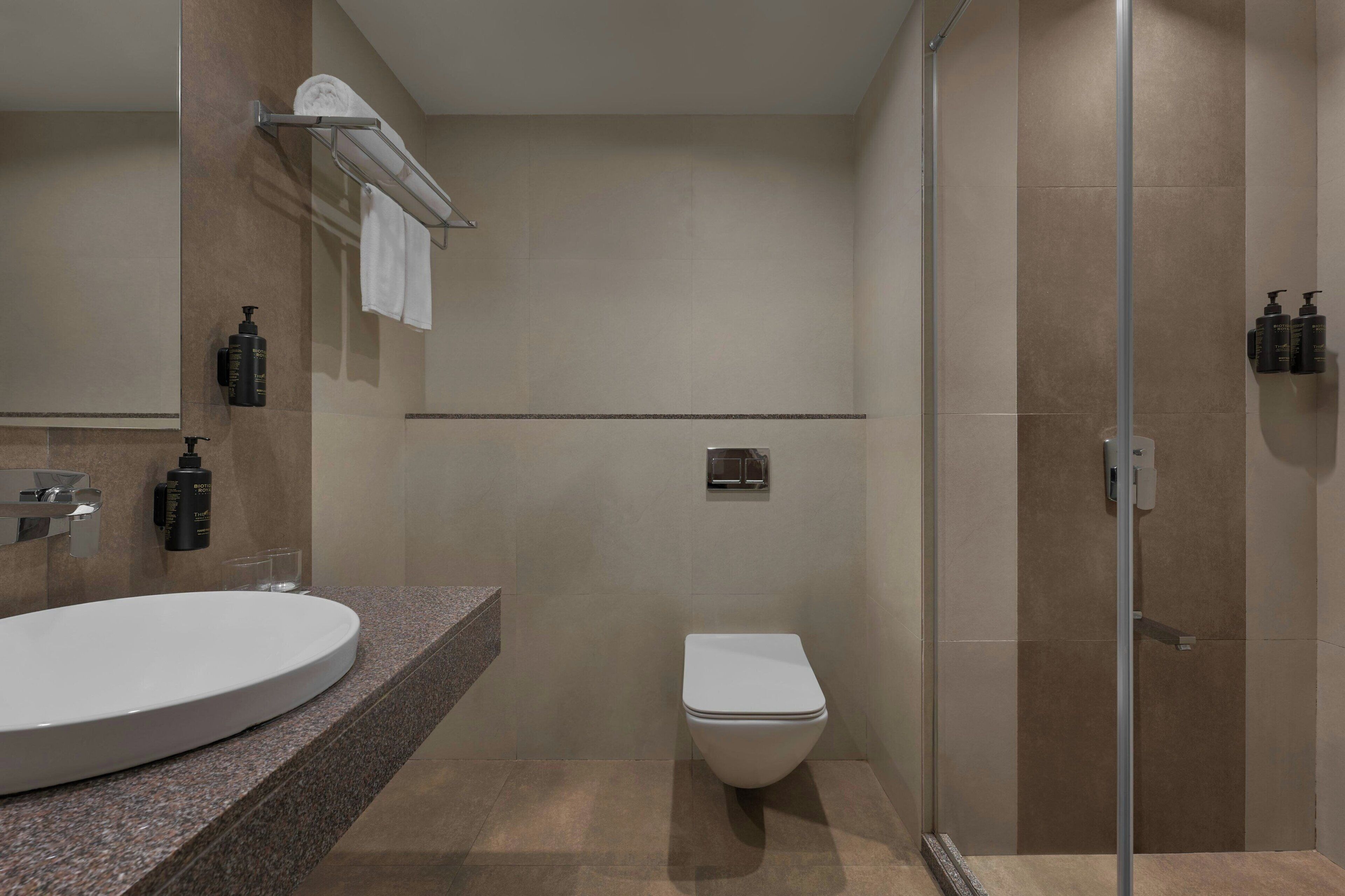 A modern bathroom with a round sink, a toilet, and a glass shower enclosure.