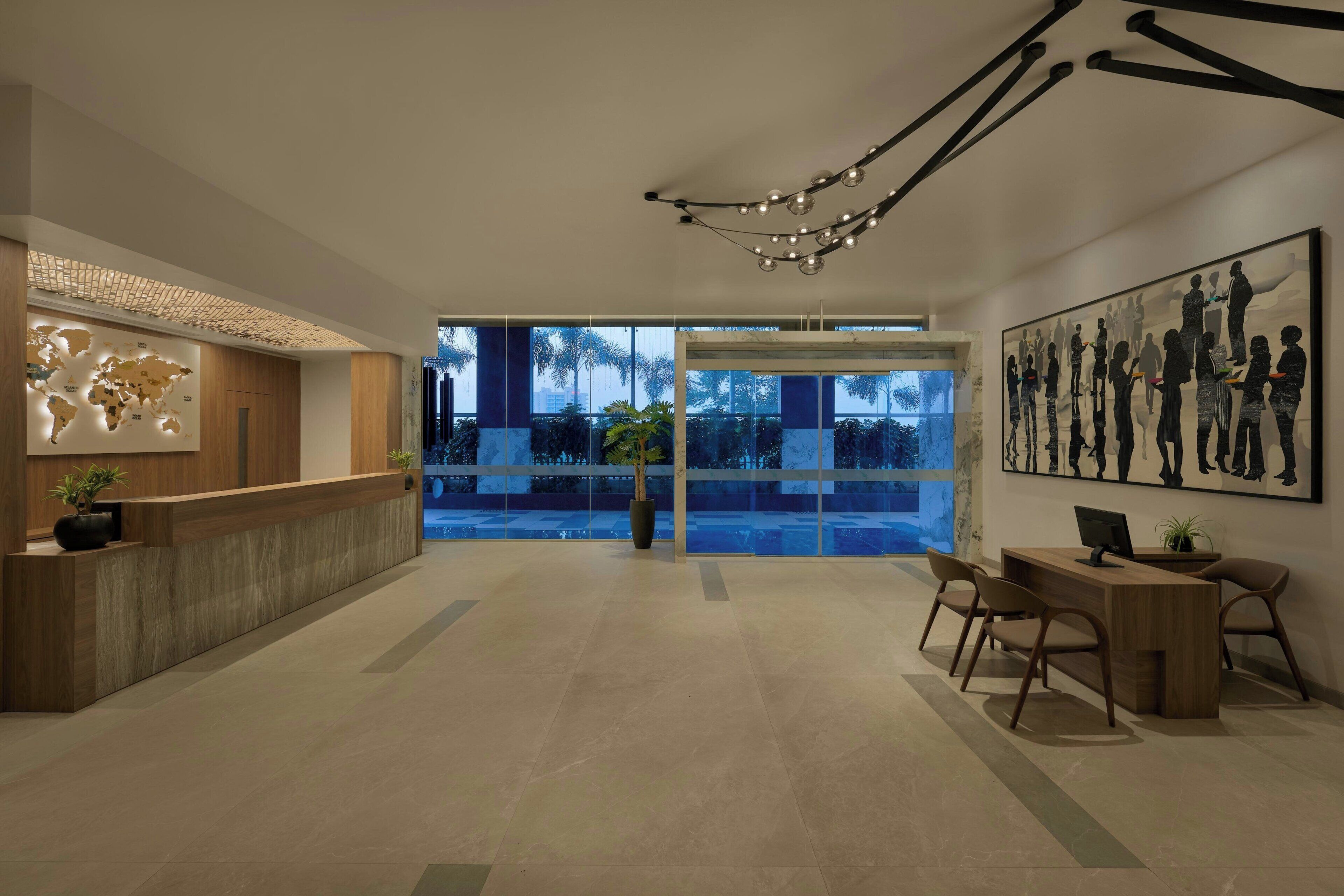 A modern reception area with a wooden reception desk, a world map, and a large artwork on the wall.