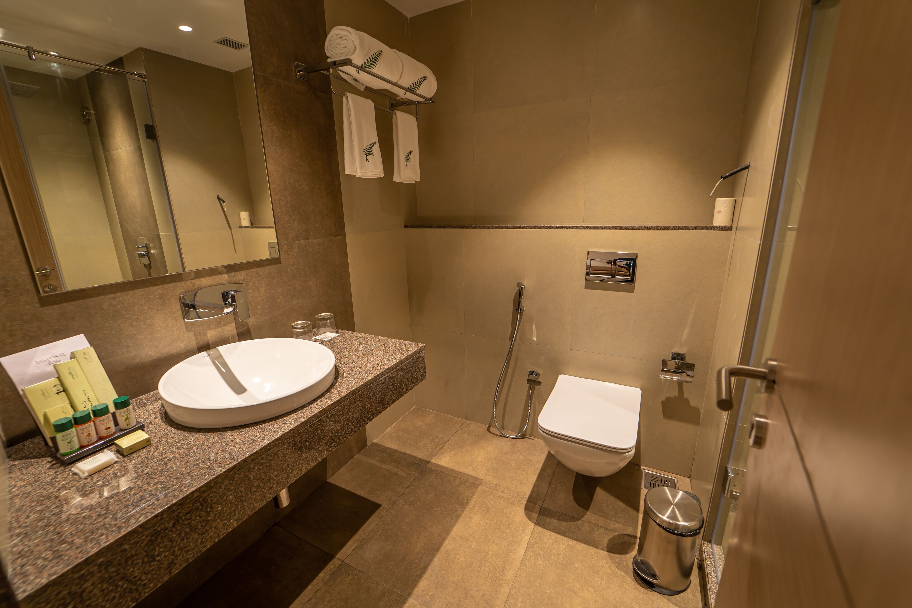 A modern bathroom with a granite countertop, a white sink, a toilet, and a glass-enclosed shower.