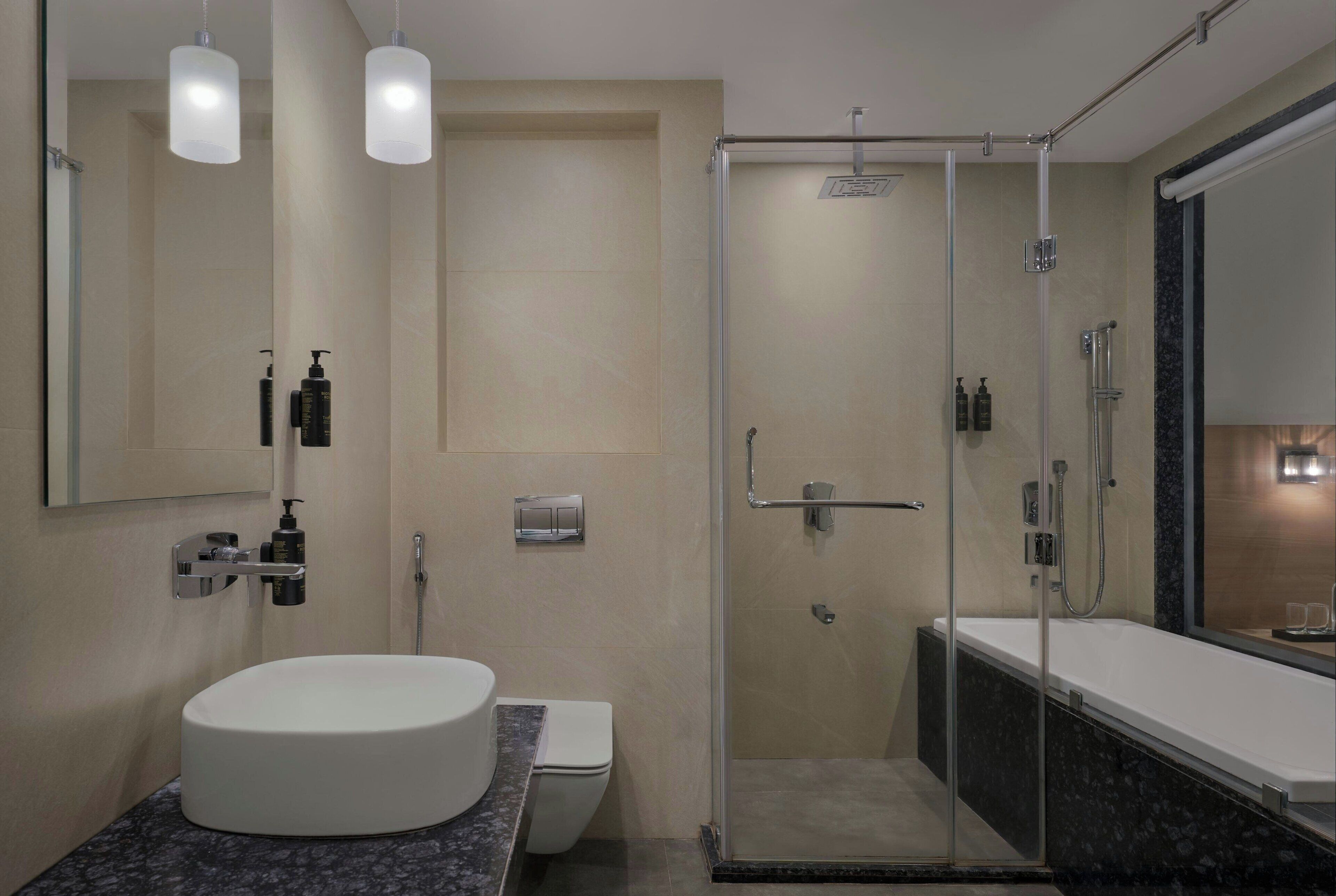 A modern bathroom with a round sink, toilet, and a glass-enclosed shower area.