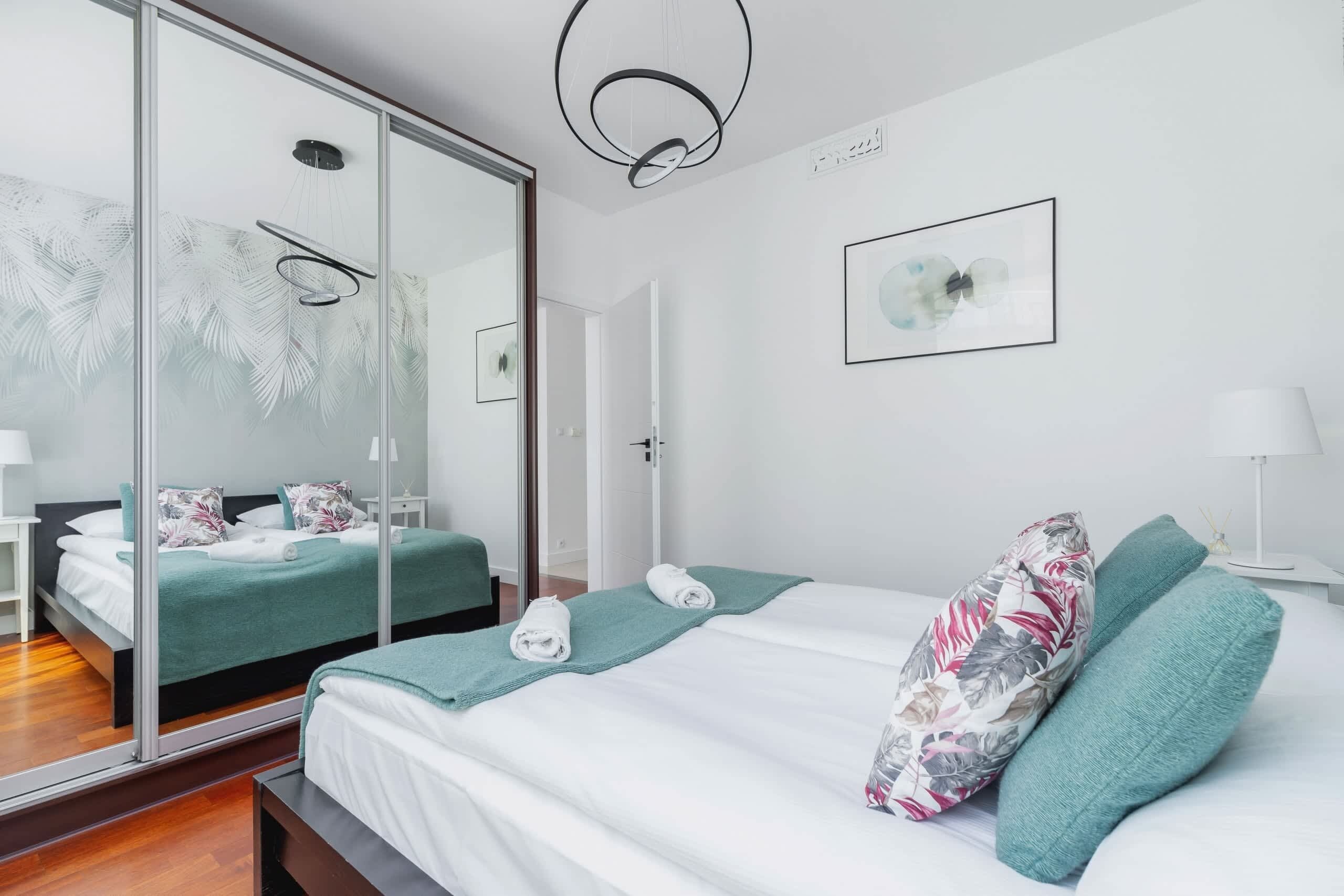 Een moderne hotelkamer met een groot bed, een douchecabine van glas, een nachtkastje met een lamp en een lijst met kunstwerk aan de muur.