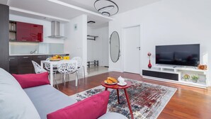 Un salon moderne comprenant un canapé, un téléviseur et un coin repas avec des chaises et une table.