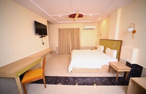 A hotel room with a bed, a desk, a chair, a TV, and a ceiling fan. - Kenth Hari Resort Dhaulpur by ShriGo Hotels (Dhaulpur)