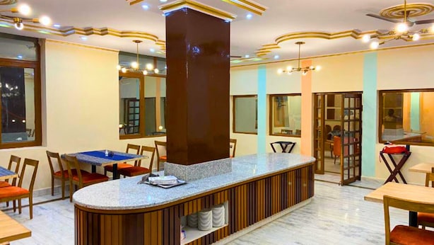 A modern restaurant with a central bar area, multiple seating options, and a decorative ceiling design. - Kenth Hari Resort Dhaulpur by ShriGo Hotels (Dhaulpur)