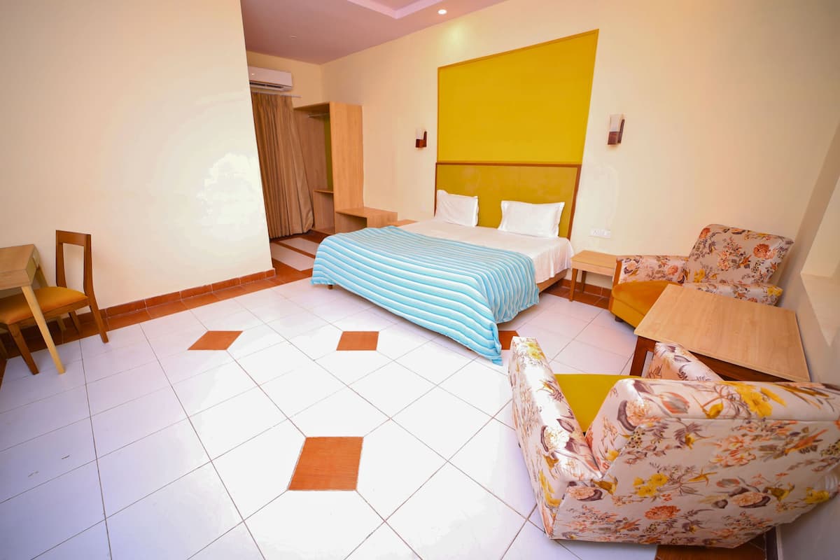 Une chambre d’hôtel comprenant un lit, une chaise, un canapé, une petite table et une armoire.