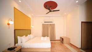 A hotel room with a bed, bedside table, and a ceiling fan. - Kenth Hari Resort Dhaulpur by ShriGo Hotels (Dhaulpur)
