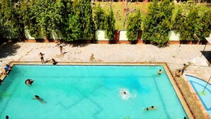 A rectangular swimming pool with clear blue water, surrounded by a concrete deck and trees. - Kenth Hari Resort Dhaulpur by ShriGo Hotels (Dhaulpur)