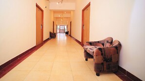 A hotel hallway with a patterned sofa, wooden doors, and a tiled floor. - Kenth Hari Resort Dhaulpur by ShriGo Hotels (Dhaulpur)