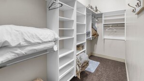 A bedroom with a bed, a closet with open shelves, and a small rug. - Ground Level Heavenly Suite | Private BBQ Patio (Hurricane)