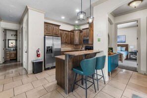 A modern kitchen with wooden cabinets, stainless steel appliances, and a central island with bar stools.
