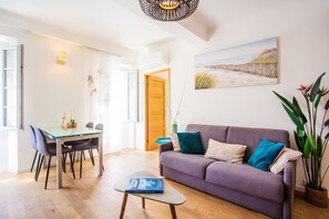 Ein modernes Wohnzimmer mit Essbereich, einem violetten Sofa und einem großen Fenster.
