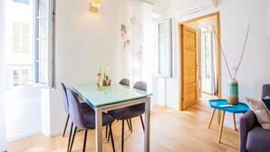 A bright room with a glass table, chairs, a wooden door, and a blue side table. - PARADISIO 2 AP4237 By Riviera Holiday Homes (Niza)