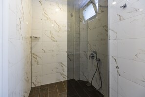 A shower area with white marble tiles and a dark wooden floor. - La Villa Celine (Kas)