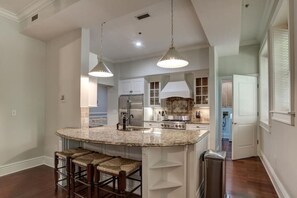 A spacious kitchen with granite countertops, stainless steel appliances, and a central island with bar stools.