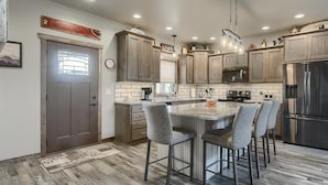 Una cocina moderna con armarios de madera, un refrigerador de acero inoxidable y una isla central con taburetes de bar.