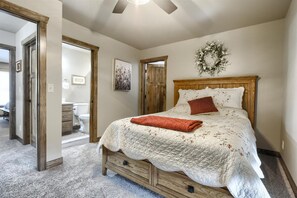 A bedroom with a wooden bed, a quilted bedspread, a red throw blanket, and a wall-mounted wreath. - 3 Level Cabin w/ Large Driveway on Paved Roads Close to Attractions! Hot Tub! (Lead)