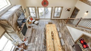Amplio espacio tipo loft con una gran mesa de madera para comedor, múltiples opciones de asientos y una chimenea.