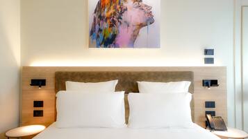 A hotel room with a large bed, two bedside tables, a headboard, and a wall-mounted artwork.