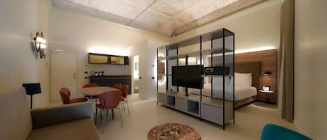 A modern hotel room with a dining area, a TV, and a sofa.