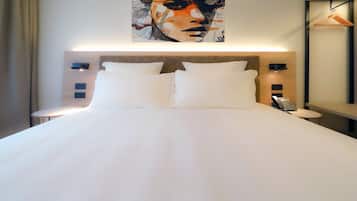 Ein aufgeräumtes Bett mit weißer Bettwäsche, einem Kopfteil, Nachttischen mit Lampen und einem an der Wand hängenden Kunstwerk darüber.