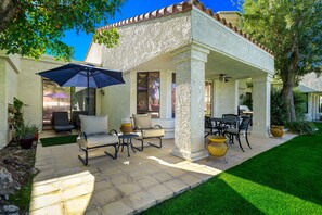 A covered patio with outdoor furniture, a ceiling fan, and a view of the backyard.
