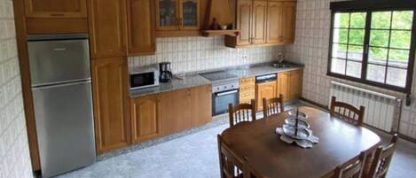 Een koelkast, een oven, een vaatwasser, kookgerei, borden en bestek