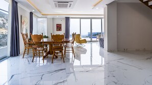 A modern dining area with a marble floor, wooden chairs, and a table.