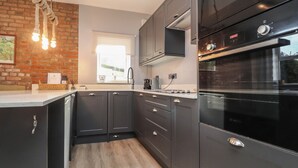 Une cuisine moderne avec des meubles de rangement aux couleurs sombres, un four encastré et une fenêtre qui laisse entrer la lumière naturelle.