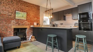 Une cuisine moderne avec un mur en briques, une cheminée et des tabourets de bar.