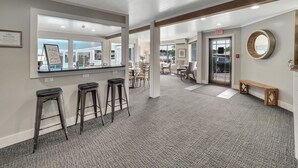 A hotel lobby with a reception desk, bar stools, a round mirror, and a seating area with chairs and tables. - 211 Pointes North | Dog Friendly | Downtown Charlevoix | Indoor/Outdoor Pool (Charlevoix)