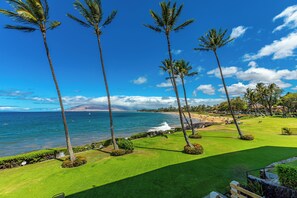 A golf course with palm trees, a beach, and the ocean in the background. - Royal Mauian #210 Ocean View, Full A/C, Great Location, Close to beaches! (Kihei)