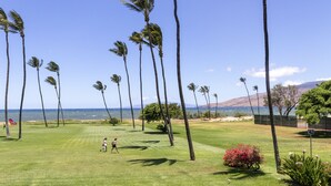 A well-maintained golf course with a clear view of the ocean and mountains in the background. - Leinaala Oceanfront #203 Panoramic Ocean View, Renovated, A/C, Great Rates! (Kihei)