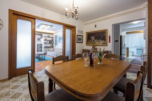 A dining room with a wooden table, chairs, a chandelier, and a painting on the wall.