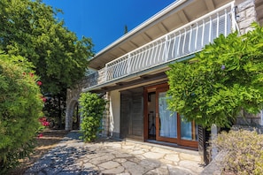 A stone building with a balcony, a wooden door, and a stone pathway.