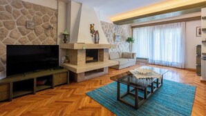 A living room with a stone wall, a fireplace, a television, a sofa, and a coffee table.