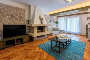 A living room with a stone wall, fireplace, television, sofa, and a coffee table.