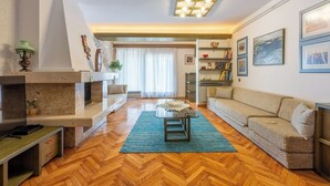 A spacious living room with a herringbone wood floor, a sofa, a coffee table, and a fireplace.