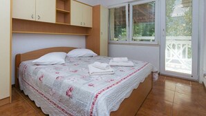 Ein Schlafzimmer mit Bett, Kleiderschrank, Fenster und Klimaanlage.