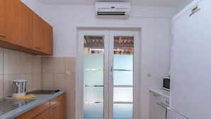 Eine kleine Küche mit Holzausstattung, einer eingebauten Mikrowelle und einer Glastür zum Balkon.