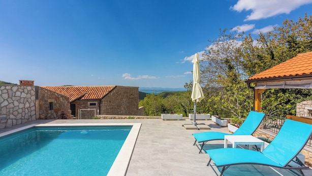 A swimming pool with lounge chairs and a stone building in the background. - Villa Green Point (Grizane)
