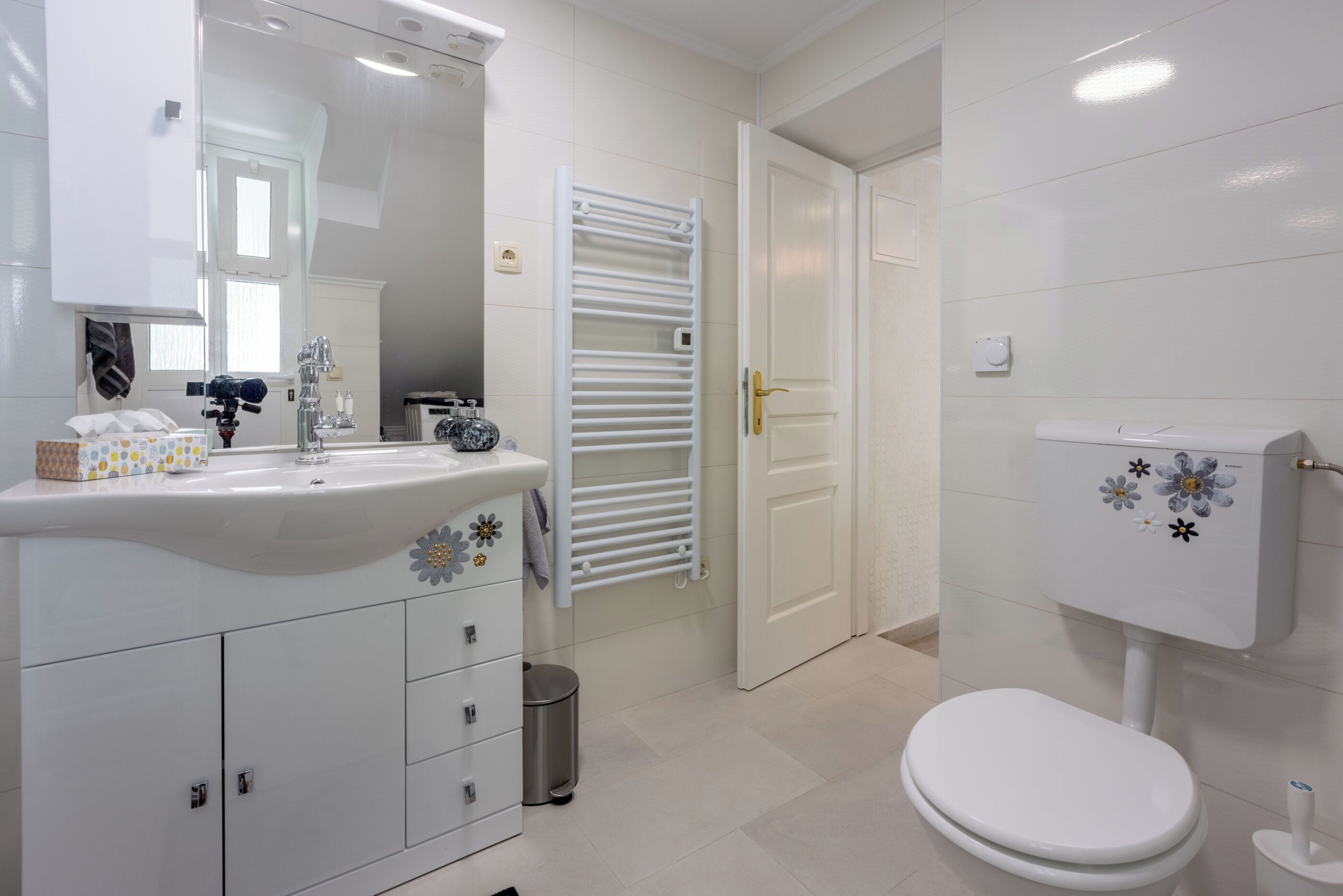 Ein modernes Badezimmer mit Waschbecken, Spiegel und Toilette in Weiß.