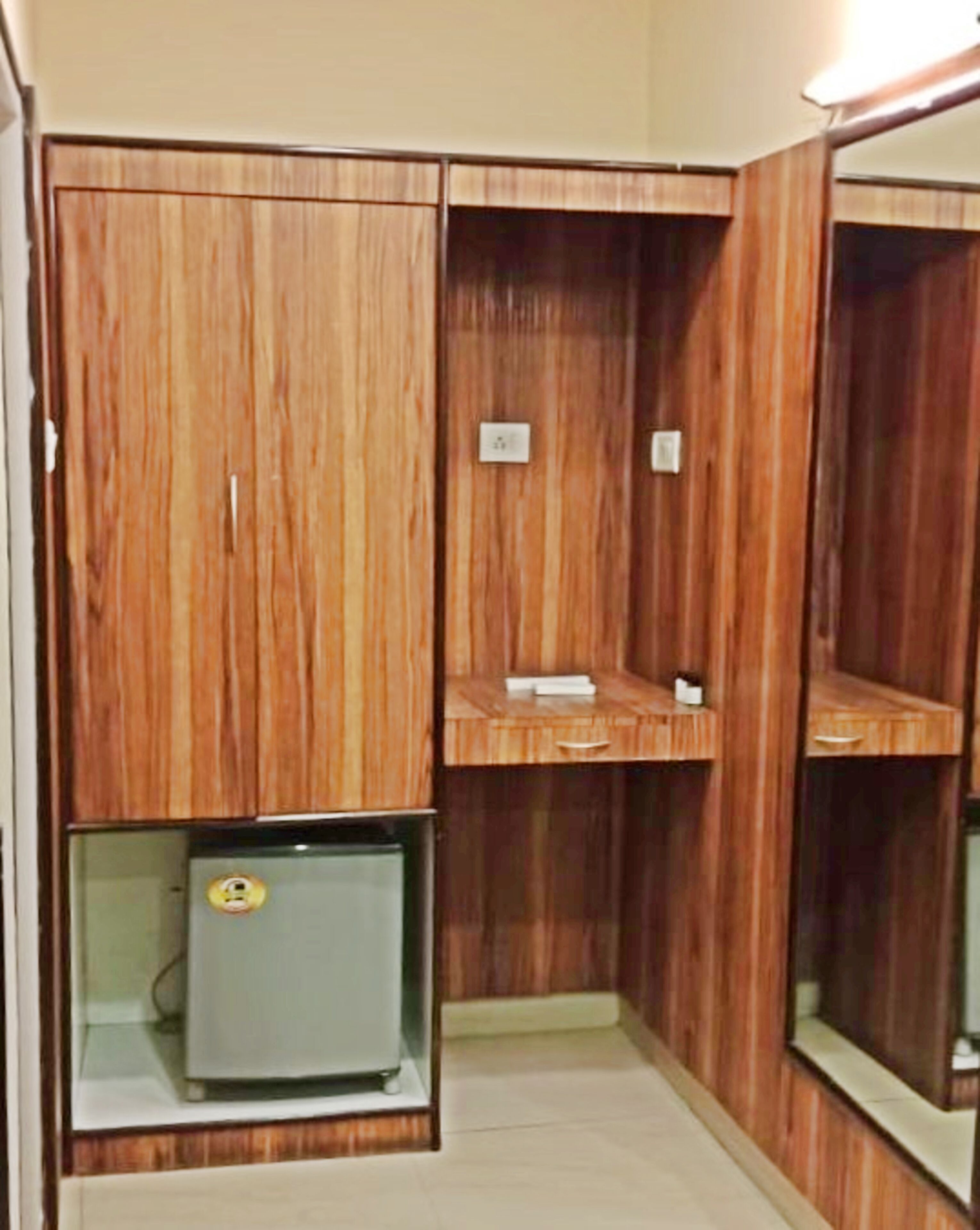 Una habitación con paneles de madera, un refrigerador pequeño y un espejo.
