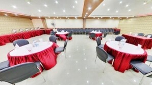 Un salón de conferencias con mesas y sillas redondas, dispuestas en forma de U.