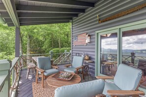 Una terraza techada con mobiliario exterior, vista al bosque y un ventanal grande.