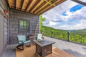Una terraza de madera con una mesa y sillas, con vistas a un paisaje verde exuberante.
