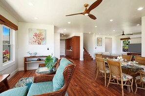A spacious living area with a dining table set for six, surrounded by wicker furniture.