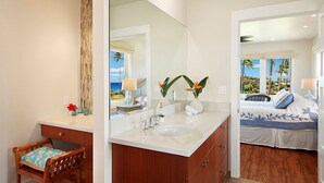 A bathroom with a large mirror, a sink, and a wooden chair.