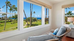A room with large windows offering a view of a golf course and the ocean.