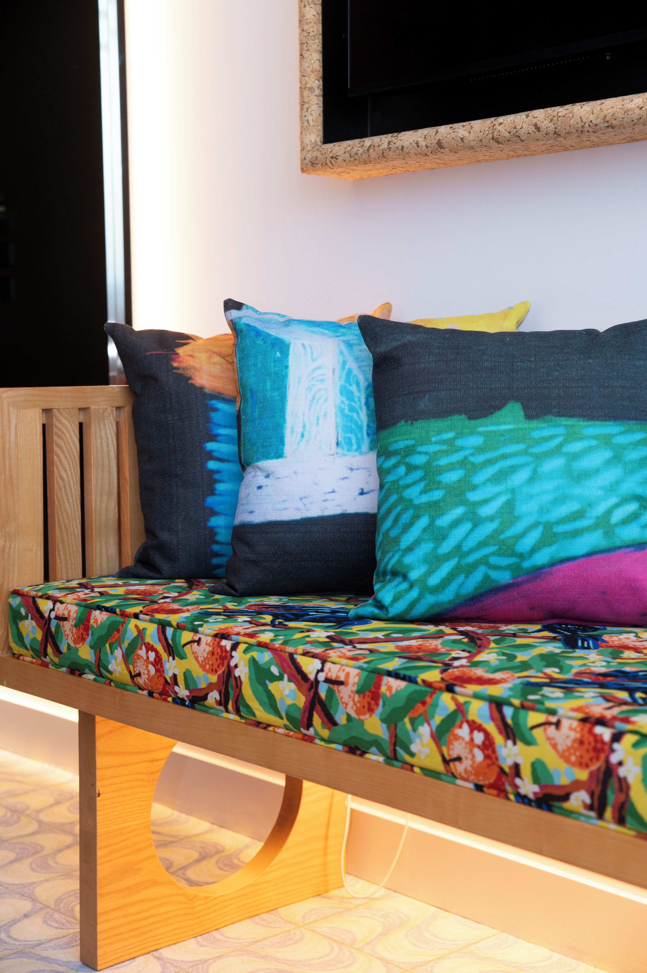 A wooden bench with colorful cushions and a patterned fabric cover.
