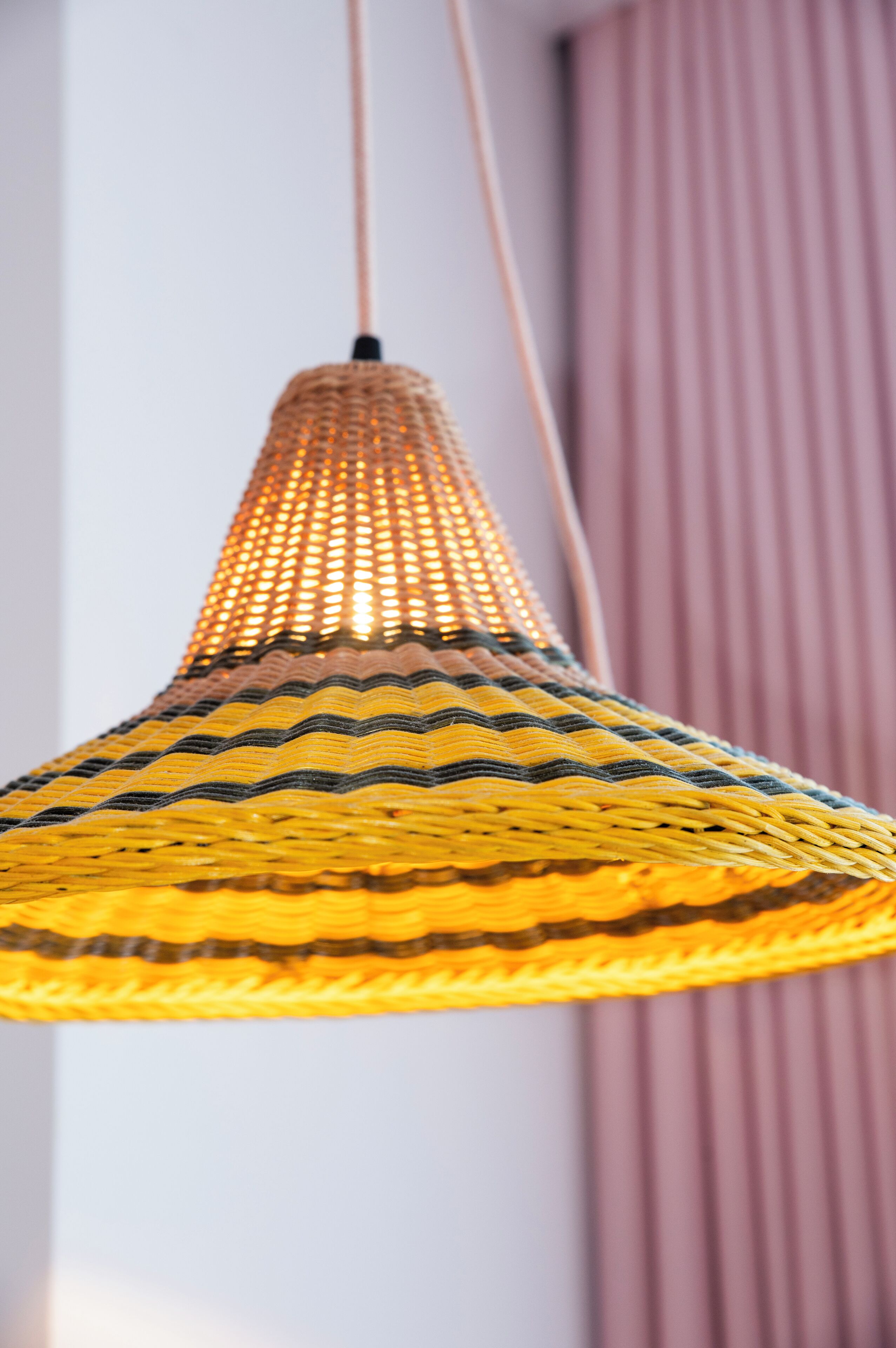 Een hanglamp met een geweven, kegelvormige kap.